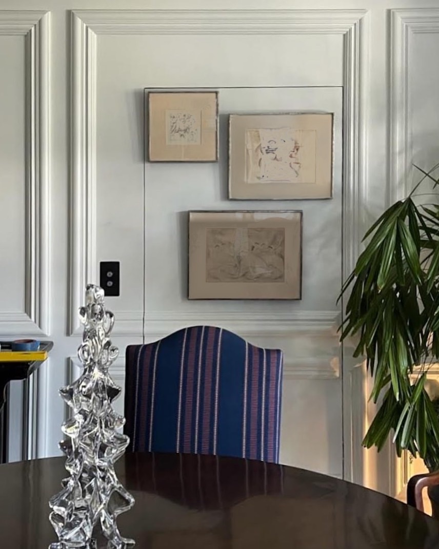 Framed works arranged across a paneled elevator door so it blends into the wall