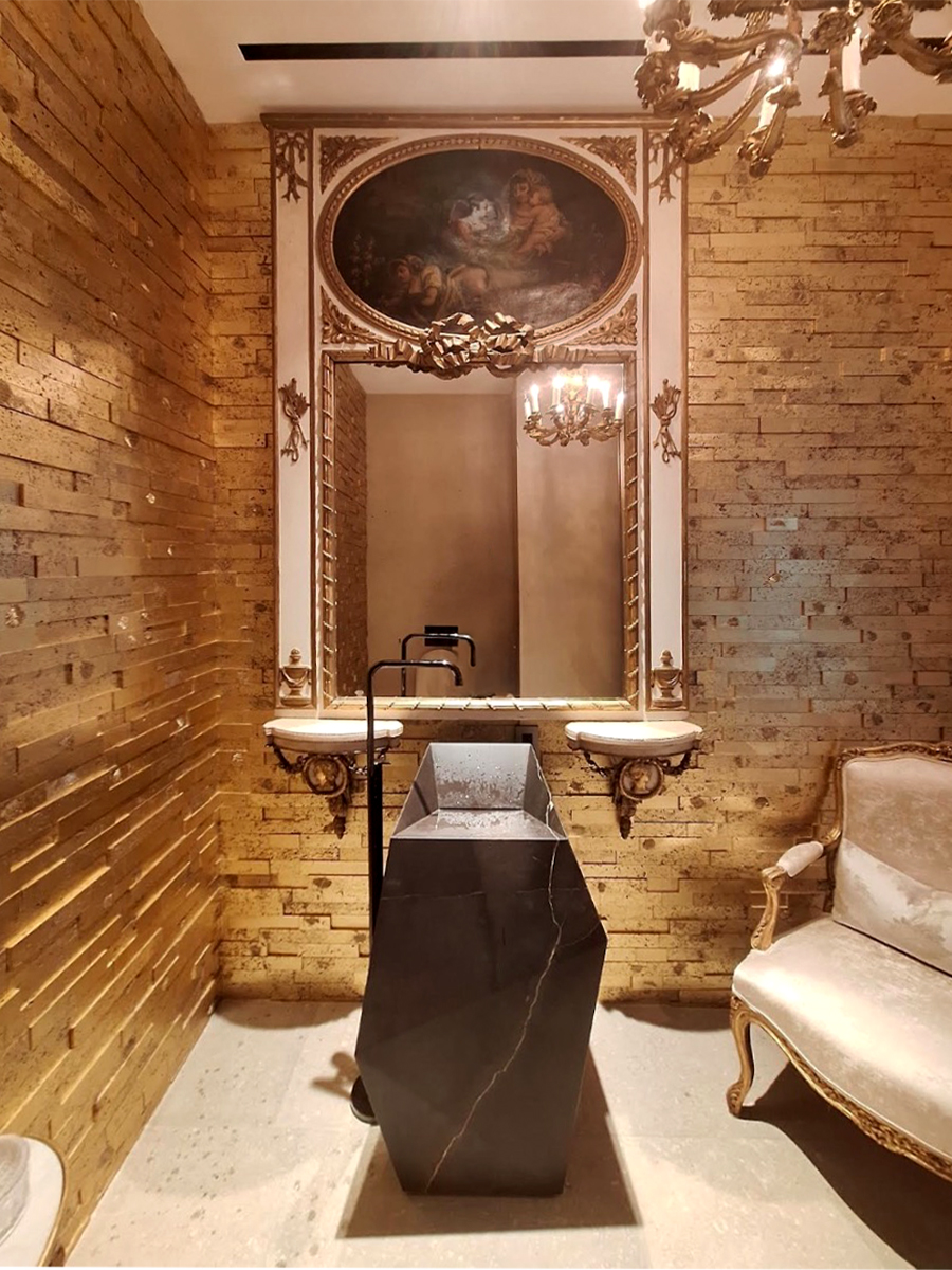 Old-master oil painting set into a gilded oval above a mirror in a gold-leaf powder room