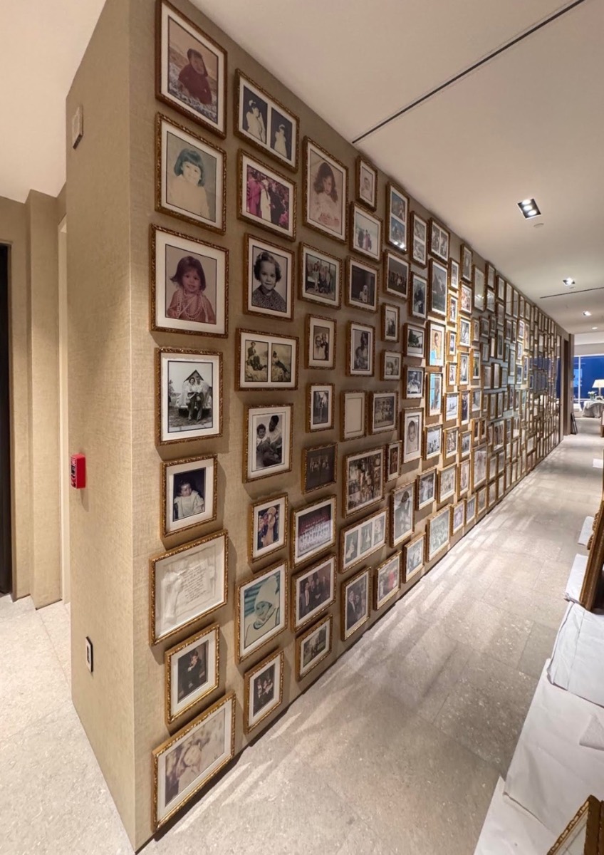 Floor-to-ceiling salon wall of gold-framed photographs installed by allART