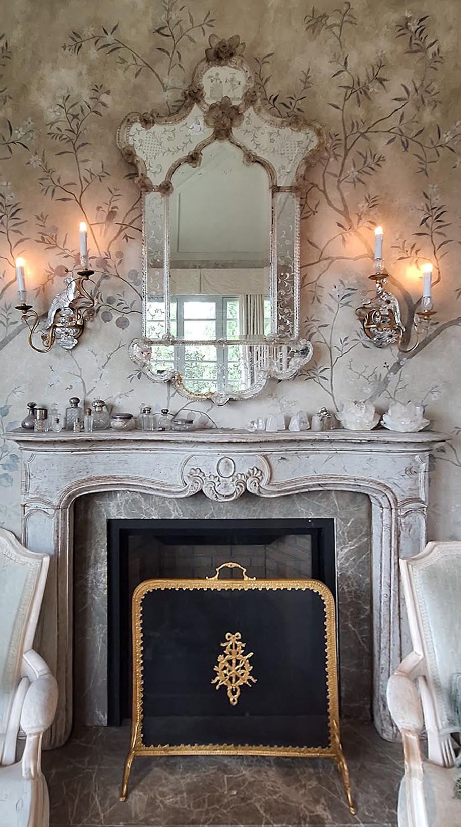 Venetian glass mirror above an antique limestone mantel on a hand-painted chinoiserie wall
