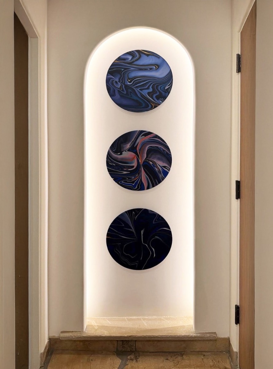 Three sculptural discs centered in a backlit archway niche