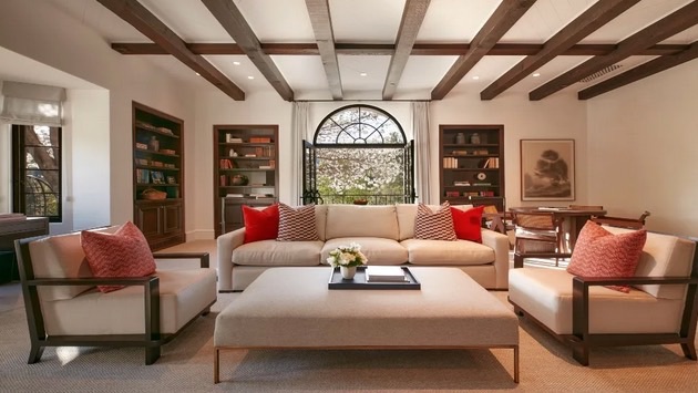 Beamed-ceiling hospitality lounge with arched window and framed art