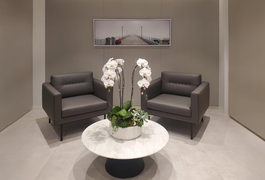 Corporate lounge with leather armchairs, marble table, and a framed panoramic pier photograph