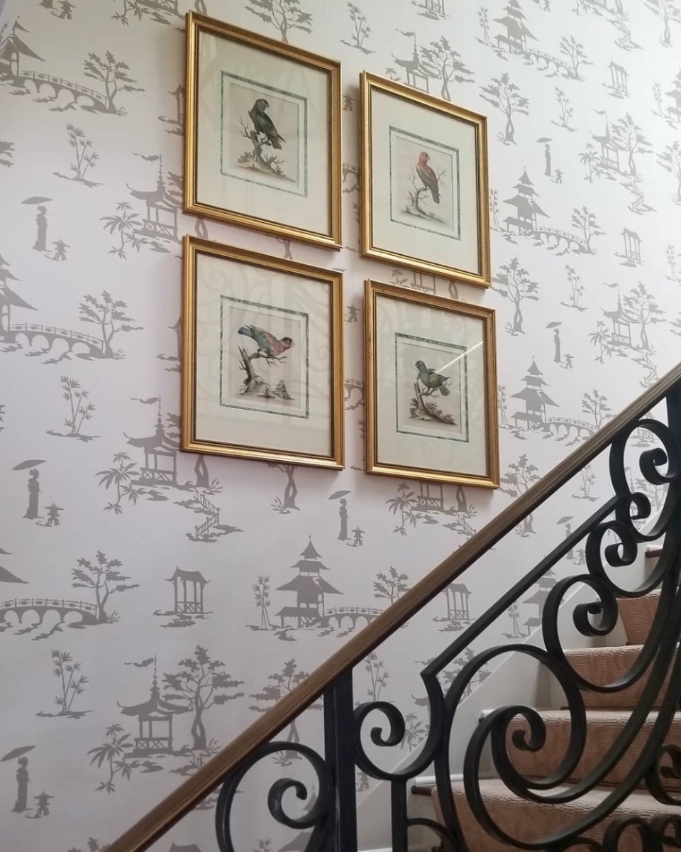Framed bird prints installed on a chinoiserie stairwell wall