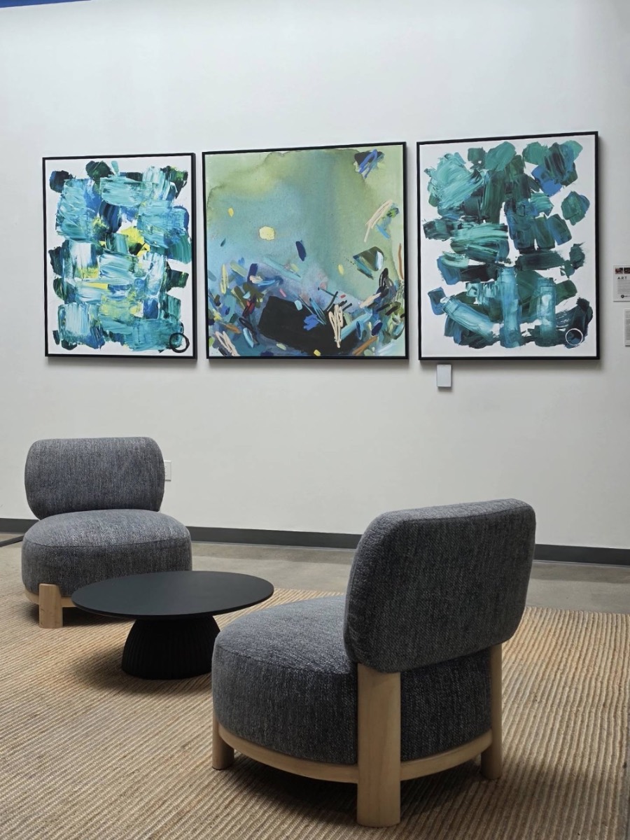 Three abstract paintings hung above lounge chairs in a lobby